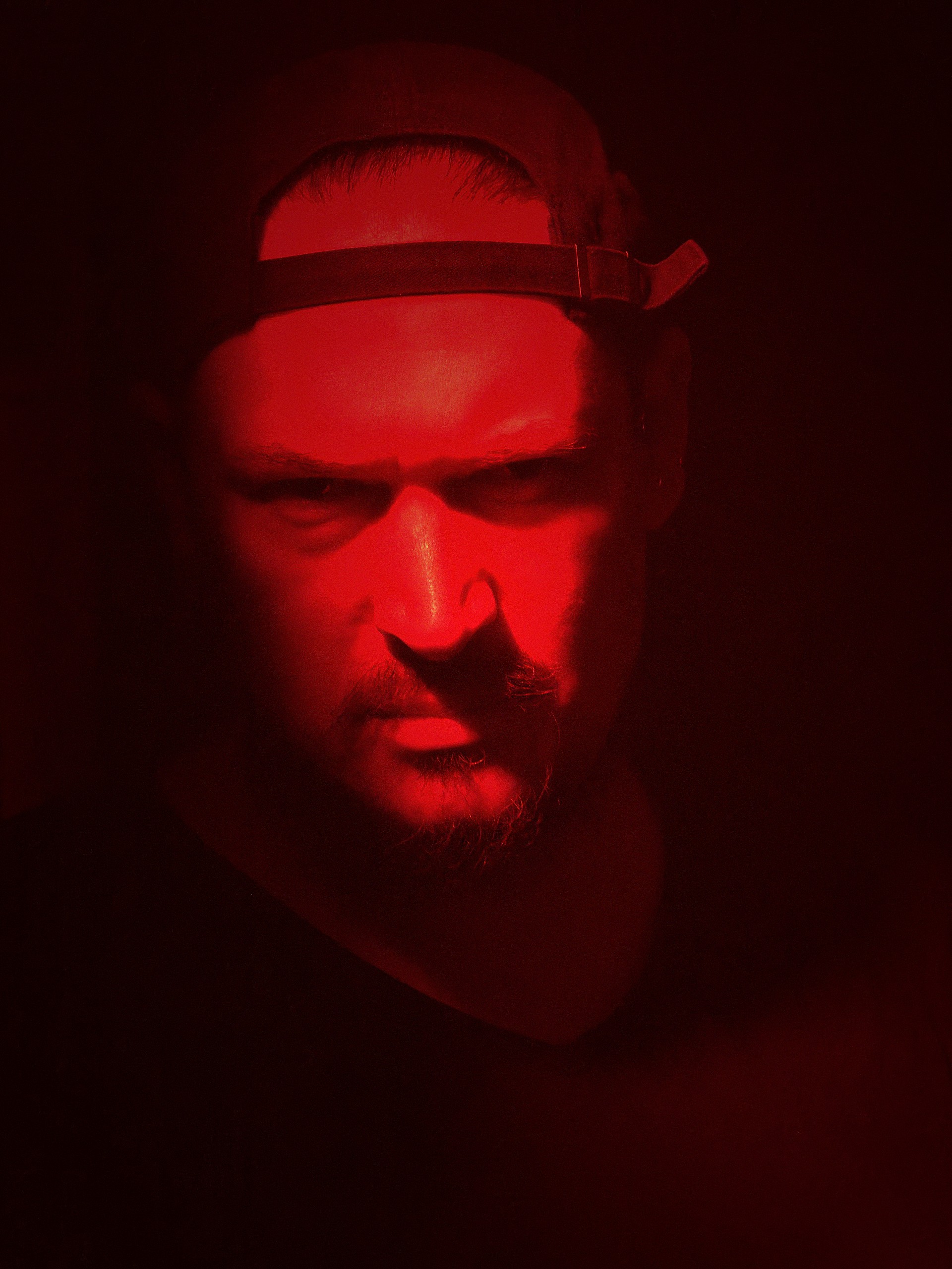 Meed / Syde portrait, backwards cap, red-lit close-up